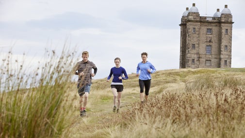 Runners in the grounds of Lyme Park, House and Garden, Cheshire with a tower in the background. Lyme Park sits in 1400 acres of parkland and has views across Manchester and the Cheshire Plain.